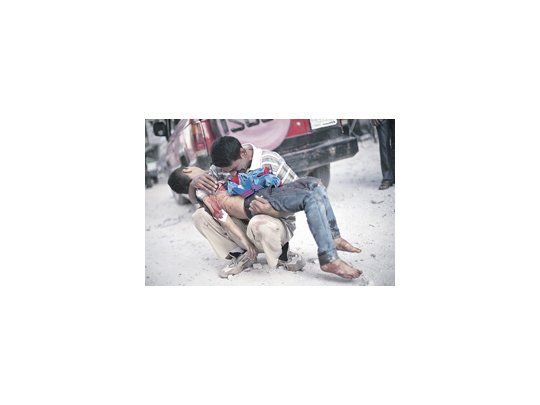 Un padre llora con el cuerpo de su hijo en brazos en las afueras del hospital Dar El Shifa de Alepo, una ciudad devastada por la guerra civil.