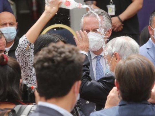 Una mujer protesta vaciandole una botella de agua en la cabeza al presidente chileno