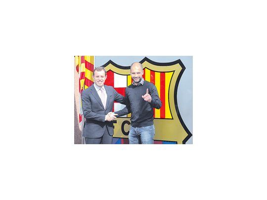 Guardiola se da la mano con el presidente Sandro Rosell y seguirá en el Barcelona hasta junio de 2012.