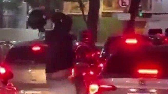 El hombre de la moto se acercó con su casco para atacar al auto a golpes.
