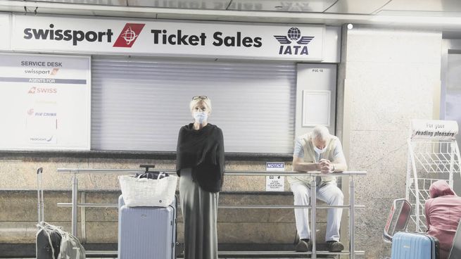 VARADOS. Pasajeros esperan a ser reubicados en vuelos no cancelados en el aeropuerto de Johannesburgo. Cada vez más países cierran sus cielos a las personas procedentes del sur de África.
