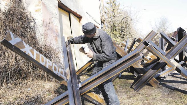 PREPARACIONES. Un grupo de civiles ucranianos pinta obstáculos antitanques en la ciudad de Uzhhorod.