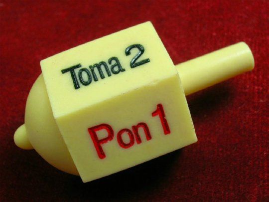 Al igual que el viejo juego de la perinola, hay una cara que dice todos toman y otra que dice todos ponen.