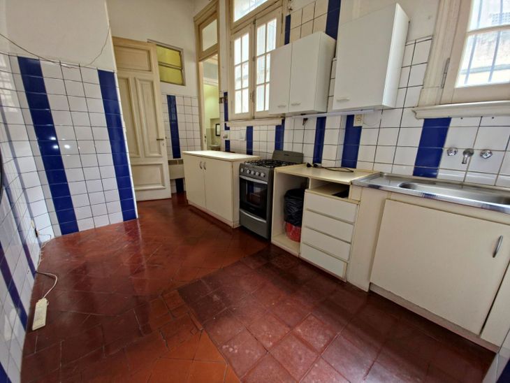 La cocina mantiene parte de su impronta original con pisos calcáreos, carpinterías de época y revestimientos cerámicos que reflejan las sucesivas intervenciones realizadas a lo largo de más de un siglo La cocina mantiene parte de su impronta original con pisos calcáreos, carpinterías de época y revestimientos cerámicos que reflejan las sucesivas intervenciones realizadas a lo largo de más de un siglo