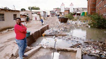 precariedad. Una mujer recoge agua en la barriada de Alexandra, cerca de Johanesburg. Más allá de toda su importancia, el final del régimen de segregación racial en Sudráfica aún no resuelve las desigualdades sociales.