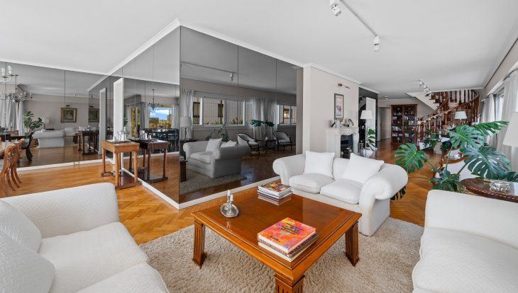 El living principal se abre con ventanales al exterior; la chimenea y la doble circulación refuerzan la idea de casa en altura El living principal se abre con ventanales al exterior; la chimenea y la doble circulación refuerzan la idea de casa en altura