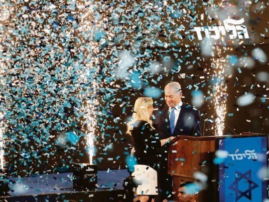 FESTEJO. Bibi Netanyahu, anoche, en medio de confetti, junto a su esposa Sara. Confía en que el escrutinio final le dé el triunfo y le permita seguir en el poder.