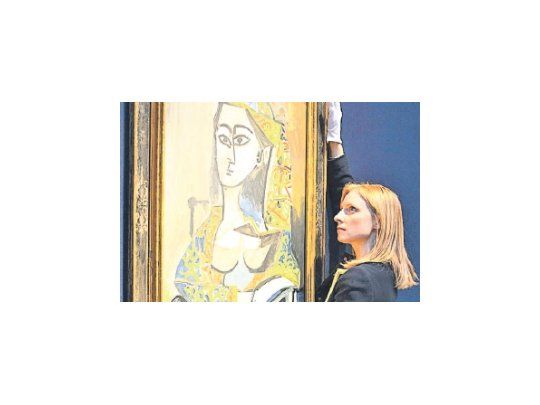 Una empleada de Christie´s exhibe “Femme au costume turc dans un fauteuil” (Mujer con traje turco en un sillón), de Picasso.