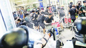 CHOQUES. La policía hongkonesa reprimió con gas pimienta a los manifestantes dentro del aeropuerto. Ellos atacaron a dos personas, que debieron ser hospitalizadas, por considerarlas espías.