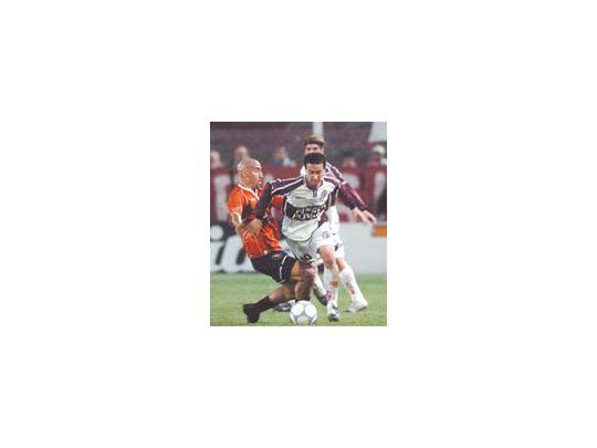 Román Díaz intenta escapar a la marca de Orteman, sin éxito. Lanús logró importante triunfo frente a Independiente.