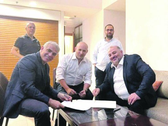ACUERDO. Una foto casera filtrada a los medios retrata el momento en el que el centrista Yair Lapid (izquierda), el líder de la derecha radical Naftali Bennett, y el dirigente del partido árabe Raam, Mansur Abas, sellan el acuerdo.&nbsp;