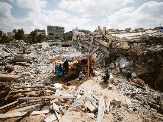 DESOLACIÓN. Once días de guerra y fuertes ataques israelíes dejaron sólo devastación en la Franja de Gaza. En la foto, un grupo de palestinos se cobijan bajo una tienda improvisada sobre los restos de su casa destruida.
