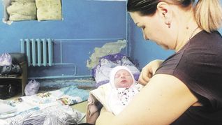 TERROR. Una mujer cuida de su hijo recién nacido en un refugio en Járkov, la segunda ciudad de Ucrania, donde los combates han recrudecido. Un grupo de familiares traslada los ataúdes de los profesores Yelena Ivanova and Yelena Kudrik, que murieron durante bombardeos en Donetsk.