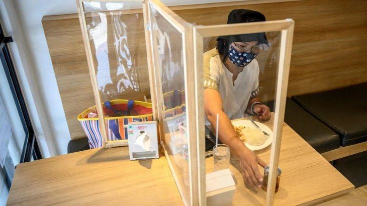 La nueva normalidad en Taiwán: una mujer come con separador de por medio. 