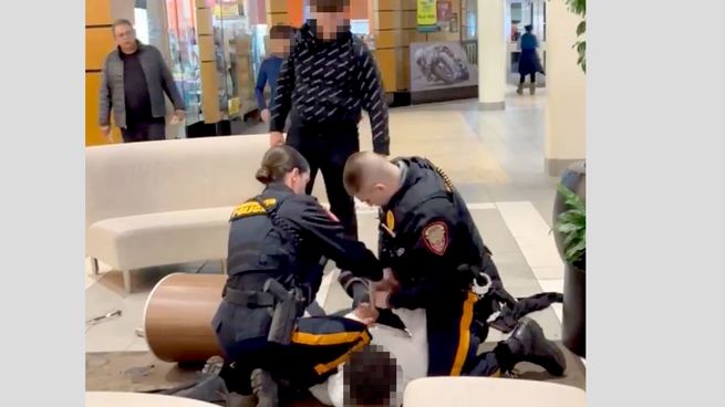 Kye, el joven negro, es esposado en el piso, mientras el joven blanco que también participó de la pelea, mira.