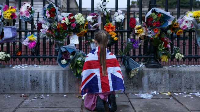 Una nena deja flores en las afueras del Palacio de Buckingham en homenaje a la reina Isabel II.