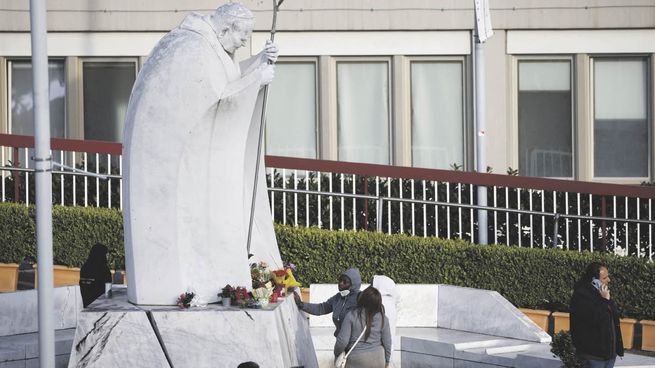 DEVOCIÓN. Un fiel toca la estatua de san Juan Pablo II. La enfermedad de Francisco conmueve a los católicos.