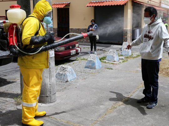 Un trabajador desinfecta a un hombre en Quito.