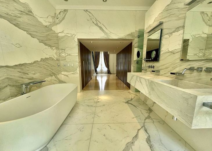 El baño de la suite principal, que forma parte de un área de casi 100 metros cuadrados, revestido íntegramente en mármol Crema Marfil El baño de la suite principal, que forma parte de un área de casi 100 metros cuadrados, revestido íntegramente en mármol Crema Marfil