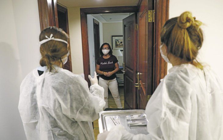 Fiebre. Dos voluntarias tocan la puerta de una habitación para tomar la temperatura.&nbsp;
