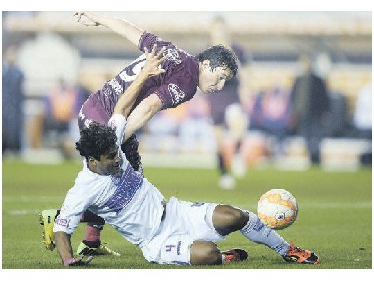 Sebastián Ariosa va al suelo para marcar al “Bicho” Aguirre. Lanús dominó, pero no tuvo contundencia.