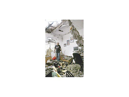 Un israelí mira los destrozos provocados por un cohete de Hizbollahen su casa de Nahariya. Los ataques sobre esa ciudaddejaron ayer un muerto.