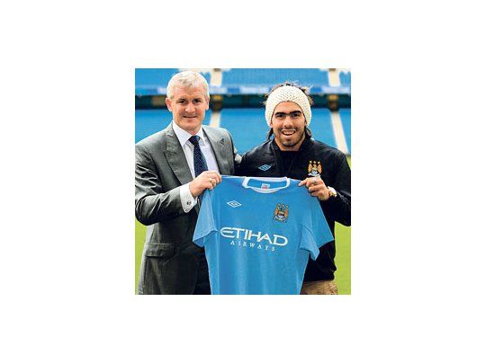 Carlos Tevez muestra su camiseta 32 junto al presidente de Manchester City. No debutó y ya es ídolo por cambiar de vereda.