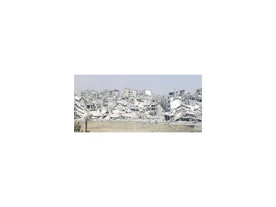 Imagen de edificios dañados y escombros en un barrio de Homs, uno de los enclaves más castigados por el conflicto.