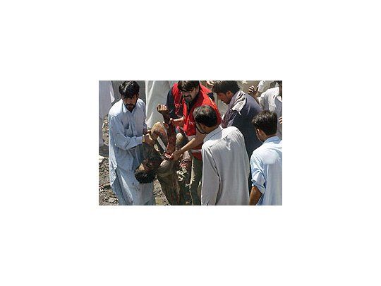 Voluntarios pakistaníes trasladan a un hombre herido luego de que explotase un coche bomba en las cercanías de un autobús.