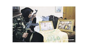 ámbito.com | Una libanesa sostiene el fusil de su hijo, un combatiente de Hizbulá muerto en la guerra civil siria. La milicia chiita combate codo a codo con las fuerzas leales a Bashar al Asad.
