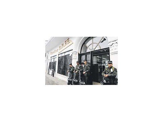 Efectivos de seguridad protegen la puerta de una financiera involucrada en un fraude de tipo piramidal en la ciudad colombiana de Popayán. Miles de personas estafadas protagonizan desde el miércoles violentos disturbios en varias ciudades.
