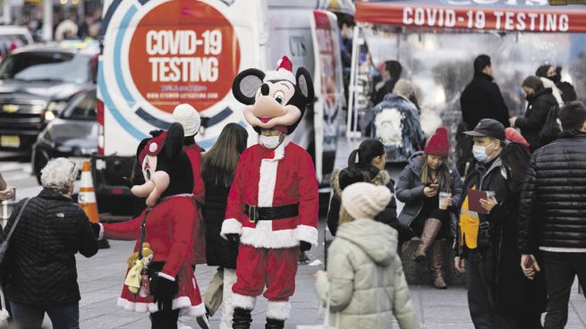 NAVIDAD CONDICIONADA. La foto habla por sí misma sobre el clima navideño peculiar de este año en Nueva York: calles con promociones comerciales, vehículos que ofrecen hisopados y personas con barbijo.