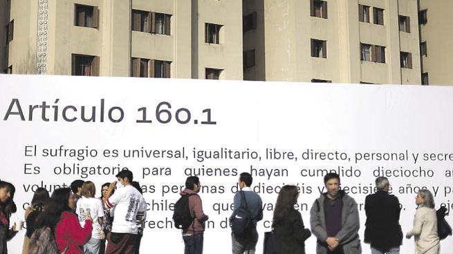 DEBATE ABIERTO. Un grupo de ciudadanos chilenos observa el texto de un artículo de la propuesta de Constitución exhibido en plena calle en Santiago.