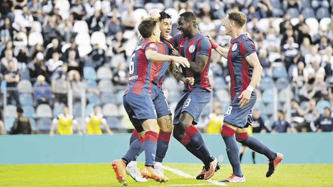 Lujo. El golazo de chilena de Bareiro, abrazado por Gattoni y por Zapata.