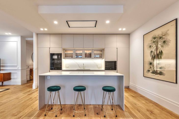 Cocina integrada de estilo contemporáneo en Canalejas, con isla y mesada de mármol sintético, alacenas laqueadas, electrodomésticos empotrados de alta gama y pisos de madera natural que refuerzan la calidez del diseño Cocina integrada de estilo contemporáneo en Canalejas, con isla y mesada de mármol sintético, alacenas laqueadas, electrodomésticos empotrados de alta gama y pisos de madera natural que refuerzan la calidez del diseño