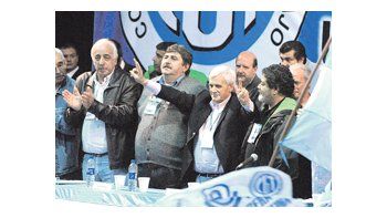 ámbito.com | El metalúrgico Antonio Caló celebra con los brazos en alto junto a su «primo» mecánico, Ricardo Pignanelli. Aplaude Roberto Fernández (colectiveros) ante la mirada de Gerardo Martínez (albañiles).