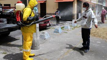 Un trabajador desinfecta a un hombre en Quito.