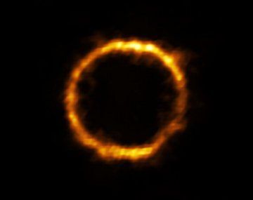 La galaxia distante aparece en las imágenes como un anillo dorado.