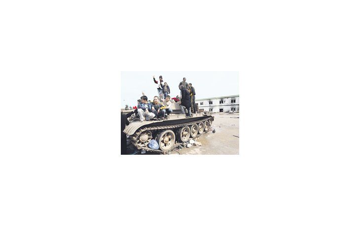 ámbito.com | Niños libios hacen señales de victoria sobre un tanque destruido en Bengasi, segunda ciudad del país. Gadafi se refugia el Trípoli, por lo que el país podría quedar desmembrado.