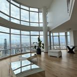 Living de grandes dimensiones en Puerto Madero con doble altura y ventanales curvos que ofrecen vistas panorámicas de la Ciudad y el río Living de grandes dimensiones en Puerto Madero con doble altura y ventanales curvos que ofrecen vistas panorámicas de la Ciudad y el río