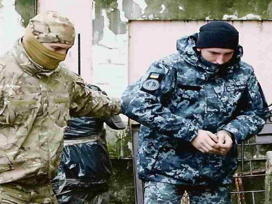 DETENIDOS. Un efectivo ruso escolta a un marino ucraniano detenido. La OTAN le exige a Rusia que ceda en su embestida, pero no obtiene respuestas.