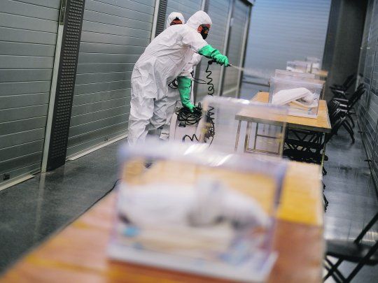 PROTOCOLO. Las elecciones se llevaron a cabo en medio de un fuerte operativo de seguridad sanitaria. Un grupo de trabajadores desinfecta las urnas en Barcelona.