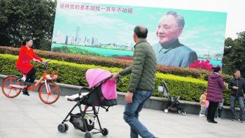 IMPULSOR. Transeuntes pasan por delante de un poster de Den Xiaoping, el impulsor de las reformas económicas en 1978, en Shenzhen, provincia de Guandong.