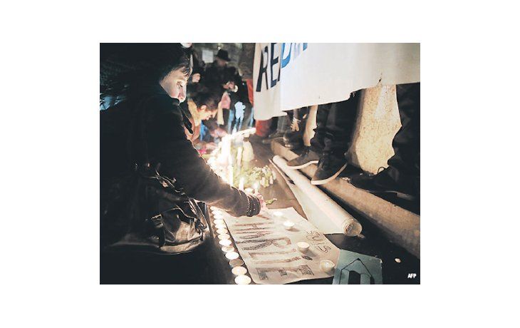 ámbito.com | Una mujer enciende una vela en la Plaza de la República, en París, en homenaje a los periodistas asesinados en la redacción de la revista satírica Charlie Hebdo.