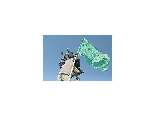 Fusil y bandera partidariaen mano, un miliciano deHamas celebra laconmocionante victoria desu partido en los comiciospalestinos.