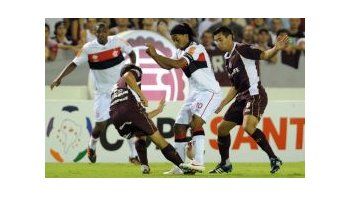 La tiene atada. La pelota se esconde entre los pies de Ronaldinho mientras los jugadores de Lanús intentan quitársela.