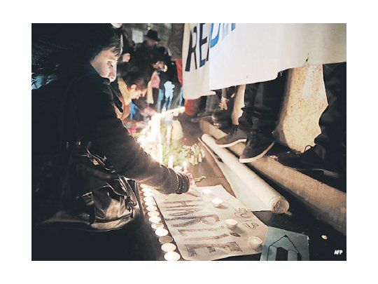Una mujer enciende una vela en la Plaza de la República, en París, en homenaje a los periodistas asesinados en la redacción de la revista satírica Charlie Hebdo.