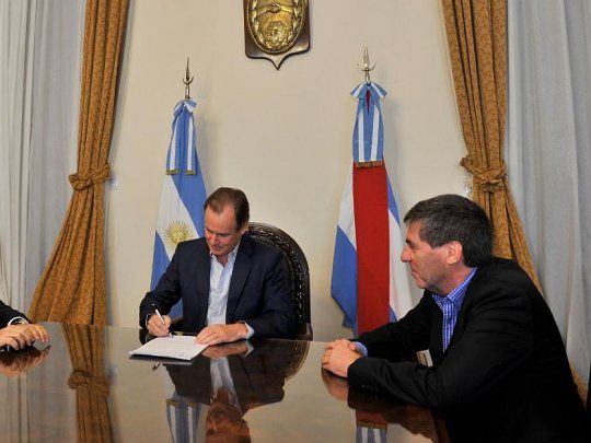 El gobernador Gustavo Bordet durante la firma del escrito, junto al Fiscal de Estado, Julio Rodríguez Signes, y el ministro de Economía, Hugo Ballay.