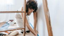 Una joven aplica una mano de pintura en el dormitorio: los cambios estéticos simples pueden mejorar la percepción del valor de una propiedad usada