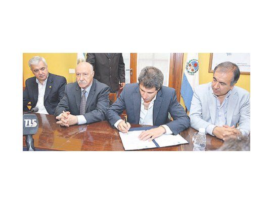 El vicegobernador Sergio Uñac y Juan José Ciácera firman los convenios acompañados por funcionarios provinciales.